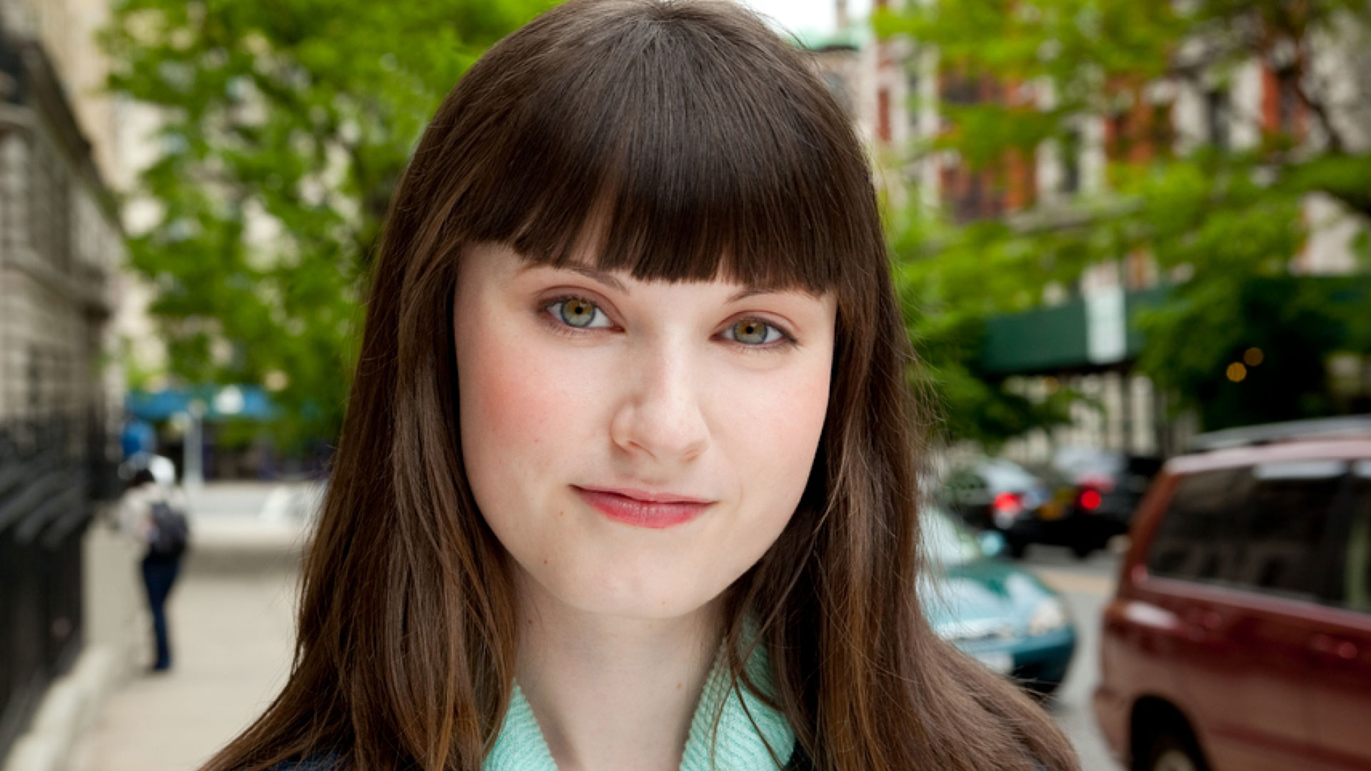 Woman wearing a jean jacket standing on a city sidewalk