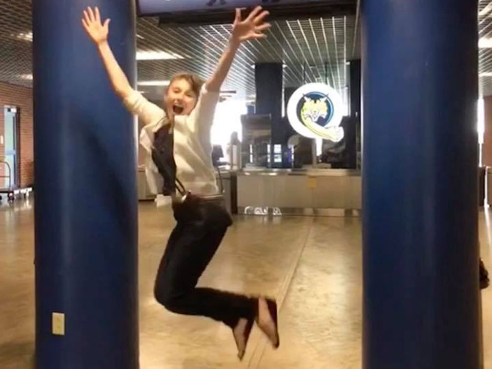 women with white sweater and heans jumping inside building